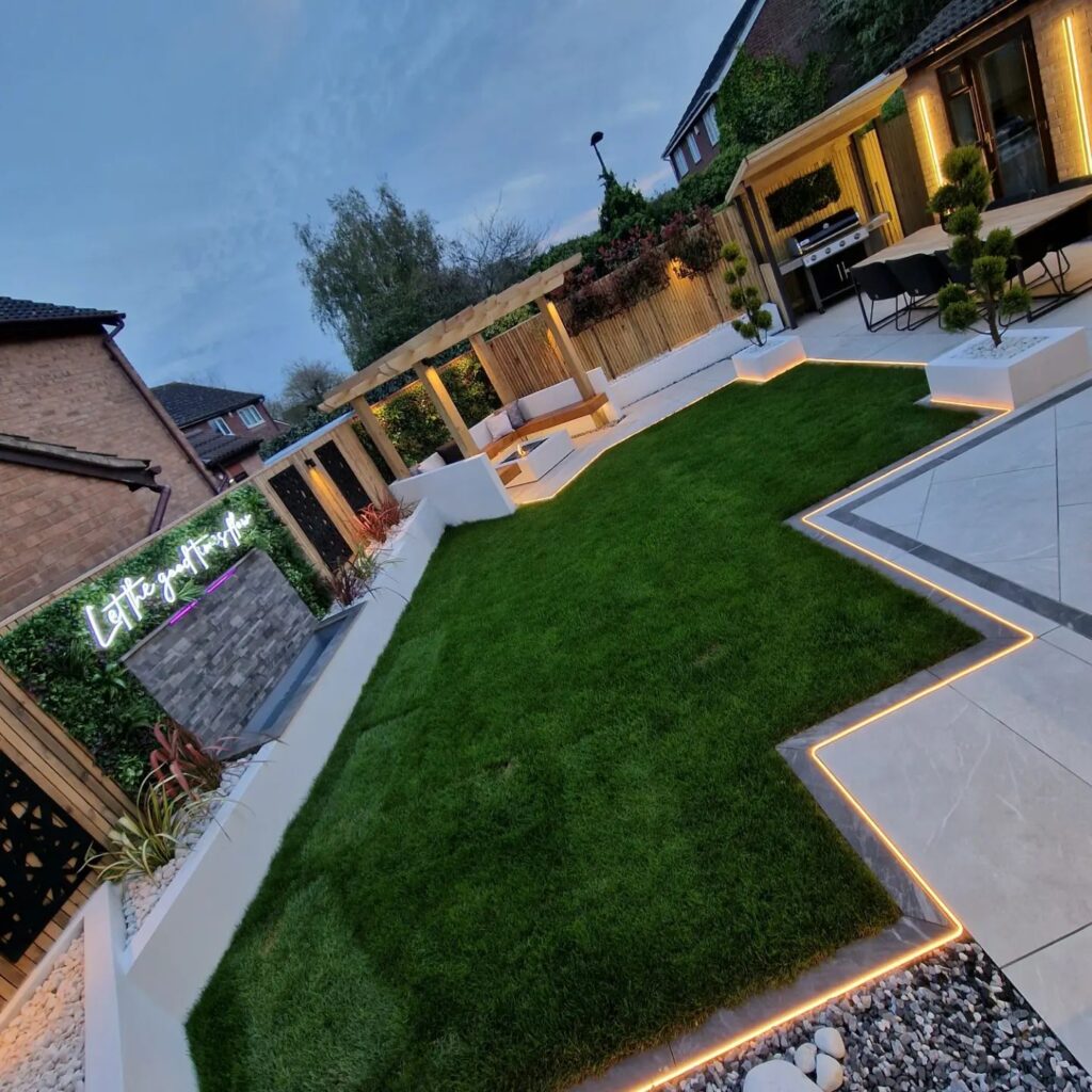 A lush green backyard with a seating lounge, barbecue area, and a Jacuzzi tub.